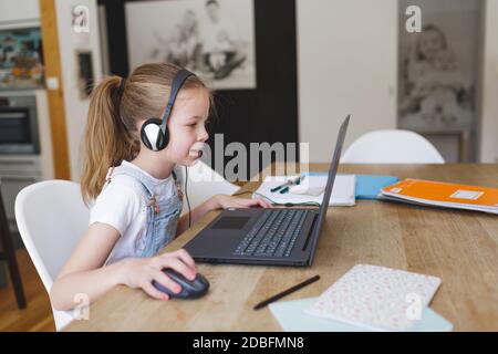 belle jeune fille avec casque est assise devant son ordinateur portable pendant le temps de corona Banque D'Images