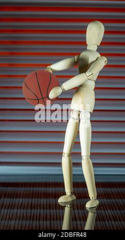 Mannequin en bois avec basket-ball devant un jalousie joue avec le ballon Banque D'Images