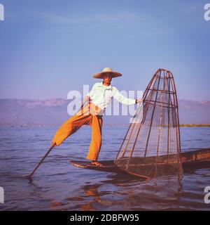 Image style hippster filtre d'effet rétro vintage de l'attraction touristique de Myanmar. Pêcheur birman traditionnel avec filet de pêche au lac Inle célèbre pour Banque D'Images
