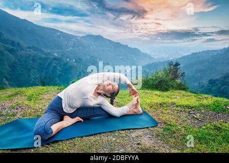 Yoga à l'extérieur - jeune femme sportive faisant du Hatha Yoga asana parivritta janu sirsasana - posture de la tête au genou tournée - po Banque D'Images