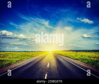 Retro Vintage style hipster image de voyage travel concept contexte - road dans blooming spring meadow sur le coucher du soleil Banque D'Images