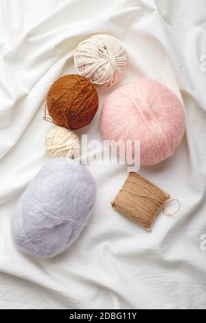 Boules de laine et mohair pour tricoter dans les couleurs pastel sur un arrière-plan de tissu Banque D'Images