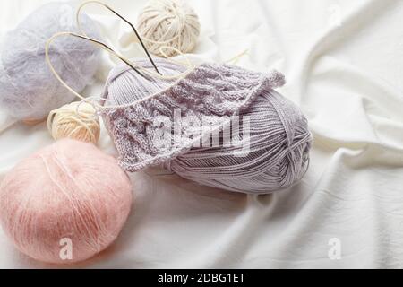 Boules de laine et mohair pour tricoter dans les couleurs pastel sur un arrière-plan de tissu Banque D'Images