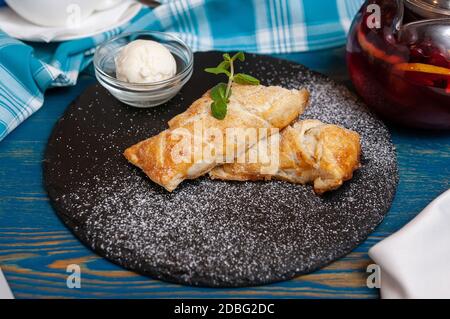 Pâte feuilletée avec pomme et sucre en poudre sur un plaque noire Banque D'Images