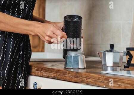 Vue rapprochée de la main d'une femme qui verse du café moulu la cafetière geyser Banque D'Images