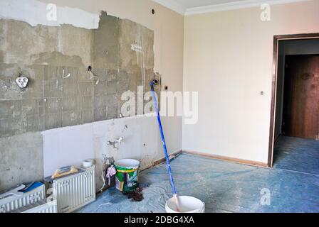 Rénovation de cuisine d'appartement partiellement peinte en cours avec seaux et brosse. Mur en béton de couleur crème. Banque D'Images