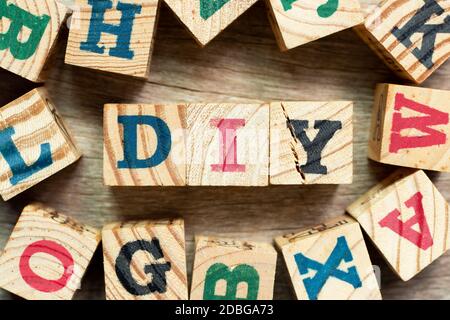 Bloc de lettres de l'alphabet dans le mot DIY (abréviation de do it self) avec un autre sur fond de bois Banque D'Images