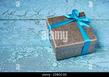 Cadeau anniversaire Noël présent concept - argent boîte cadeau avec ruban bleu sur fond de bois peint en bleu Banque D'Images