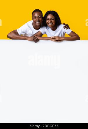 Un couple afro-américain heureux s'est penché sur un tableau vertical blanc Banque D'Images