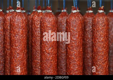 Bâtonnets de salami ou saucisses accrochés sur les cordes dans la maison de fumée. Banque D'Images