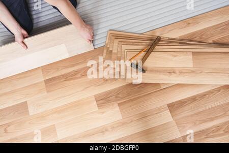 Installation de plancher laminé, détails sur les mains d'homme tenant des carreaux de bois, sur la couche de base en mousse blanche. Banque D'Images