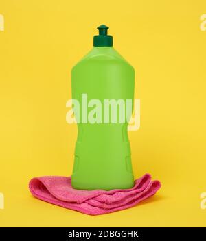éponges rectangulaires pour lave-vaisselle de cuisine rose et bouteille en plastique vert avec détergent, fond jaune Banque D'Images