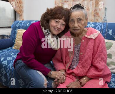 Portrait d'une femme de cent ans avec sa travailleuse sociale qui la vérifie régulièrement, chez elle à East Harlem, New York. Banque D'Images