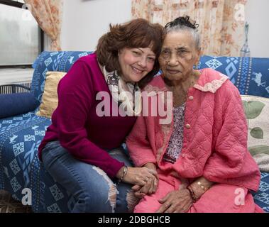 Portrait d'une femme de cent ans avec sa travailleuse sociale qui la vérifie régulièrement, chez elle à East Harlem, New York. Banque D'Images