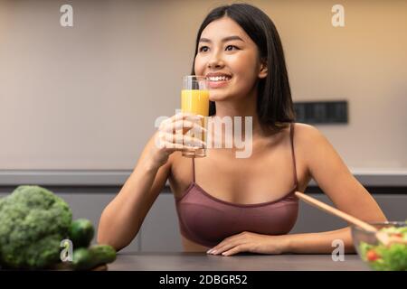 Femme boire du jus perdre du poids sur le régime assis dans la cuisine Banque D'Images