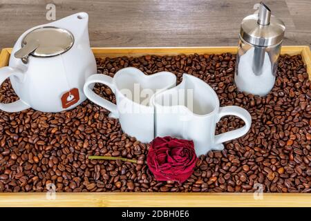 Un ensemble de tasses en forme de coeur sur un plateau avec des grains de café Banque D'Images