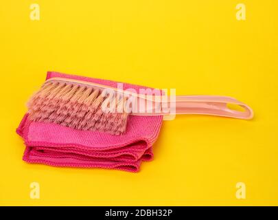 brosses en plastique rose et chiffon pour nettoyer la maison sur fond jaune, gros plan Banque D'Images