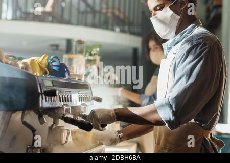 Le barista moderne travaille avec l'équipement pendant la prise de distance Banque D'Images