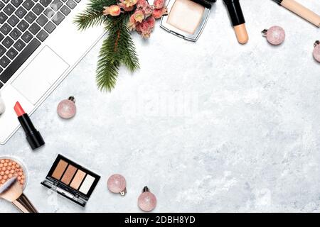 Cosmétiques décoratifs et outils de maquillage sur fond de marbre avec ordinateur portable. Concept d'achat en ligne. Composition de cadre avec espace de copie. Sapin de Noël Banque D'Images