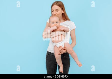 Une jeune mère heureuse et un petit garçon dans une couche, une famille s'amusant ensemble sur un fond bleu isolé Banque D'Images