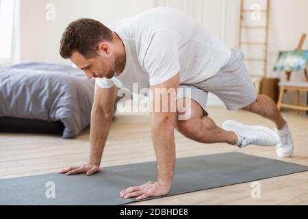 Guy faisant de l'exercice de planche de course sur le plancher dans la chambre Banque D'Images