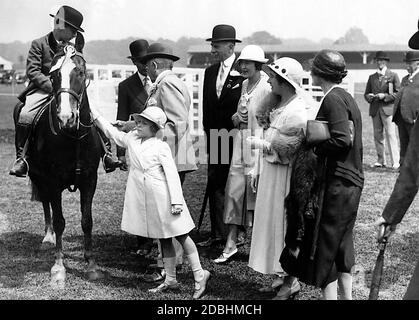 Elizabeth II petant un cheval au Royal Horse Show à Richmond, Surrey. De gauche à droite : le roi George V. (légèrement caché), le duc d'Athlone et sa femme, la marquise de Cambridge et la reine Elizabeth. Banque D'Images