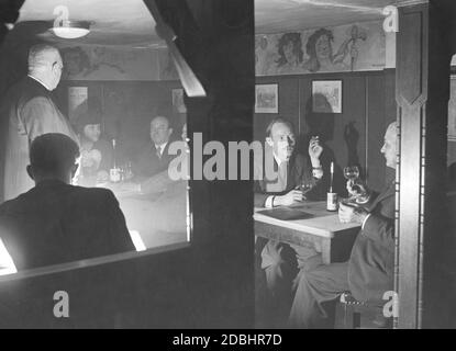 La cave à vin bien connue et populaire Lutter und Wegner était située à Charlottenstrasse 49, à l'angle de Franzoesische Strasse à Berlin-Mitte. La photo de 1936 montre un coin fumé de la cave, où messieurs et une dame sont assis ensemble. La peinture murale sur la droite est de Hans Baluschek. Banque D'Images