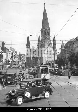 'La photo montre l'église du souvenir Kaiser Wilhelm à Berlin au moment des Jeux Olympiques en 1936, avec l'agitation de la Hardenbergstrasse, Joachimsthaler Strasse traversant en premier plan. Sur la droite en face de l'église se trouve la Maison Romanisches avec le Gloria-Palast. Sur la gauche se trouve la Haus Germania et le zoo Ufa-Palast am. Un tramway de la ligne 5 ''Aussenring'' traverse la photo.' Banque D'Images