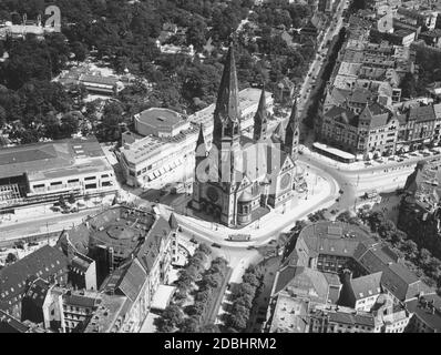 La photo montre l'église Kaiser Wilhelm Memorial à Auguste-Viktoria-Platz (aujourd'hui: Breitscheidplatz) à Berlin en 1938, avec Budaapester Strasse, Tauentzienstrasse, Rankestrasse, Kurfuerstendamm et Hardenbergstrasse menant à la place (dans le sens des aiguilles d'une montre). La place est bordée par les bâtiments: Zweites Romanisches Haus (en haut à droite), Romanisches Haus (en bas à gauche), Ufa-Palast am Zoo (à gauche), Capitol am Zoo (juste à côté) et une partie du jardin zoologique (en haut à gauche). Banque D'Images