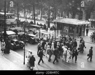 Les piétons traversent la rue Unter den Linden à Berlin à l'intersection avec Friedrichstrasse en 1929. Sur la droite se trouve une petite maison avec des informations sur Bad Kissingen. Un bus à impériale de la ligne 11 dessert Hermann-Platz à Neukoelln. Banque D'Images