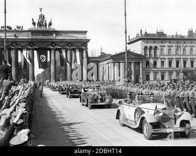 Le 15 septembre 1933, le Conseil d'Etat prussien a été repris comme un organe purement consultatif des socialistes nationaux et s'est réuni pour sa première session à l'Université Humboldt de Berlin. La photo montre l'entrée des conseillers de l'État prussien par la porte de Brandebourg accrochée au drapeau de la croix gammée, acclamée par une foule de personnes montrant le salut d'Hitler. Dans la première voiture, une Mercedes-Benz W10 (type Mannheim 370) avec des plaques d'immatriculation de Berlin, siège le ministre prussien, le président Hermann Goering (2e rangée à gauche) et le chef d'état-major de sa Ernst Roehm (à droite). Derrière elles se trouve une Mercedes-Benz W22 (type Banque D'Images