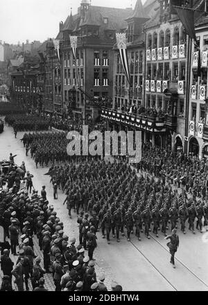 Vue sur les formations de la RAD passant devant Adolf Hitler (à gauche dans la Mercedes) sur la place Adolf-Hitler-Platz au Congrès du Parti nazi à Nuremberg. Les armoiries de la ville de Nuremberg pendre des toits des bâtiments adjacents. Banque D'Images