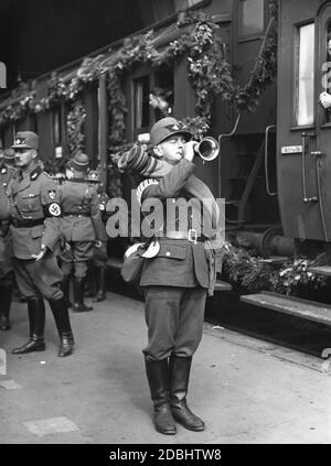 Un membre du Service national socialiste du travail utilise une trompette pour donner le signal de monter à bord du train spécial décoré quittant Berlin à 15 heures pour le Congrès du Parti nazi à Nuremberg, sur lequel se déplace le Gau 9 du Service du travail. Banque D'Images