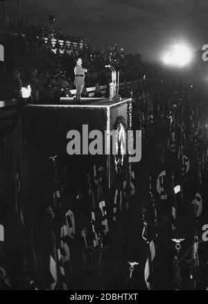 Adolf Hitler prononce un discours au Congrès du Parti nazi de Nuremberg devant un rassemblement de masse des organisations politiques du NSDAP. En dessous de lui sont des porteurs de swastika. Banque D'Images