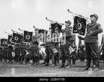 Les trompettes du Labour Service sonnent l'appel de la FAD sur le Zeppelin Field pendant le Congrès du Parti nazi à Nuremberg, derrière eux sont des batteurs. Les fanions avec swastikas et l'insigne du Service du travail de Reich sont attachés aux instruments à vent. Banque D'Images