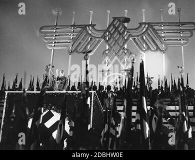 Adolf Hitler prononce un discours au Congrès du Parti nazi de Nuremberg devant un grand aigle impérial avec la croix gammée et entouré de drapeaux de la croix gammée. Banque D'Images
