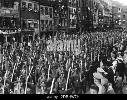 A l'occasion du Congrès du Parti nazi de Nuremberg, les formations du Service du travail de Reich défilent dans la ville qui a été décorée de drapeaux swastika, ici dans la Faerberstrasse. Banque D'Images