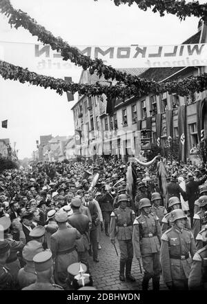 'Entrée du régiment de Doeberitz à Neustrelitz. La photo montre des spectateurs, marchant des soldats de la Wehrmacht avec des sifflets et des trompettes, des drapeaux swastika et une bannière avec l'inscription ''Welcome''. Banque D'Images