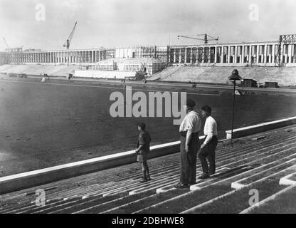 Trois hommes regardent les tribunes nouvellement érigées sur le champ de Zeppelin, sur le site du rassemblement du Parti nazi à Nuremberg, qui sont construites pour le Congrès du Parti nazi. Banque D'Images