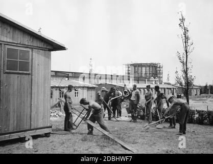 Des membres du Service du travail participent aux travaux de construction de l'exposition Deutschlandestellung (Allemagne) à Kaiserdamm à Berlin. En arrière-plan, les casernes du Service du travail. Banque D'Images