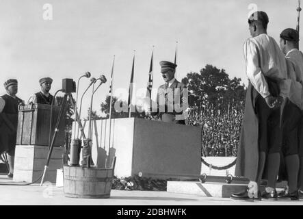 Adolf Hitler prononce un discours lors de la cérémonie révolutionnaire du nouveau Kongresshalle sur les lieux du rassemblement du parti nazi à Nuremberg. À gauche de la pierre de fondation se trouve la cassette, derrière elle Reichshandwerksmeister (Maître de l'artisanat de Reich) Wilhelm Georg Schmidt avec d'autres artisans en costume traditionnel. Banque D'Images