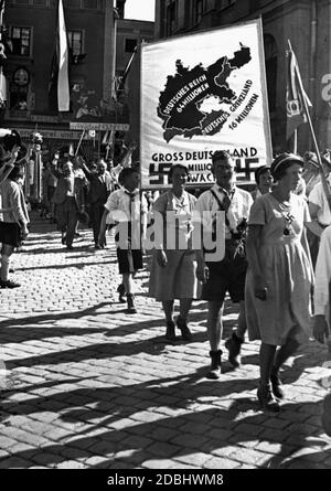 'Les participants à la parade à l'occasion de la conférence VDA à Passau portent une bannière sur laquelle sont représentés le Reich allemand et la ''frontière allemande'' avec les chiffres de population 64 millions et 16 millions. Au-dessous, entre deux swastikas, se trouve l'inscription ''Grande Allemagne. 80 millions d'éveillés''. Derrière la bannière se trouve une délégation de l'Alte Gymnasium à Nuremberg. Au premier plan, une femme porte une croix gammée comme décoration. Sur le bord gauche de la photo se trouve un groupe d'hommes en costume traditionnel.' Banque D'Images