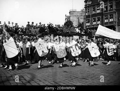 Lors de la deuxième fête de la conférence de Whitsun du VDA à Koenigsberg, les participants marchent dans les rues décorées avec goût de la ville, ici en face de la Konzerthaus. Les armoiries (ici des Allemands hongrois: Ofenpest, Stuhlweissenburg (Szekesfehervar), Fuenfkirchen (Pecs), oedenburg (Sopron), Gran (Esztergom), Raab (Gyor) sont portées par les filles du BDM comme signe de la connectivité des nationalités allemandes. Dans les tribunes : le ministre Reich Bernhard Rust et Hans Steinacher de la VDA. Banque D'Images