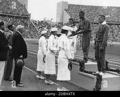 Cérémonie des gagnants du sprint de 400 mètres aux Jeux olympiques d'été de Berlin en 1936. L'athlète américain Jesse Owens reçoit la médaille d'or. Jesse Owens a établi un nouveau record du monde avec un temps de 39.8 secondes. Le président du Comité International Olympique, le comte Henri de Baillet-Latour, est également présent (2e à partir de la gauche). Banque D'Images