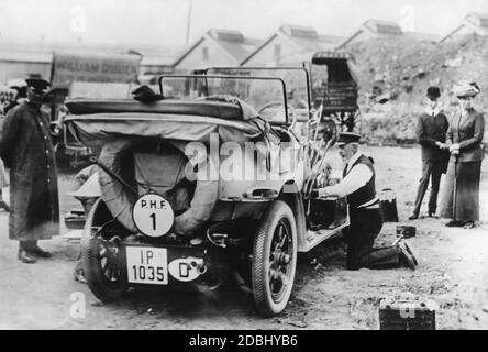 Sur cette photo de 1911, le prince Henry de Prusse (à droite, à genoux) répare la voiture avec laquelle il a participé à la dernière Prinz-Heinrich-Fahrt. La voiture portant le numéro 1 est un modèle de production de la marque Benz (Benz 8 avec 18 hp) avec l'identifiant IP de la province de Schleswig-Holstein. Banque D'Images