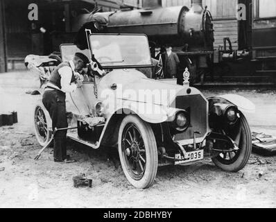 Le prince Henry de Prusse (avant gauche) répare sa voiture de course, avec laquelle il participe au dernier Prinz-Heinrich-Fahrt en 1911. Heinrich actionne le levier de vitesses, qui était à l'extérieur de la voiture, le frein à main est suspendu au sol derrière lui. La voiture est un modèle de production de la marque Benz (Benz 8 avec 18 ch). Le Prinz-Heinrich-Fahrt de 1911 n'était pas une course, mais un aller-retour. Banque D'Images