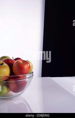 ensemble de différentes variétés de pommes dans un récipient en verre transparent. Sur fond noir et blanc pommes rouges dans une assiette sur blanc Banque D'Images