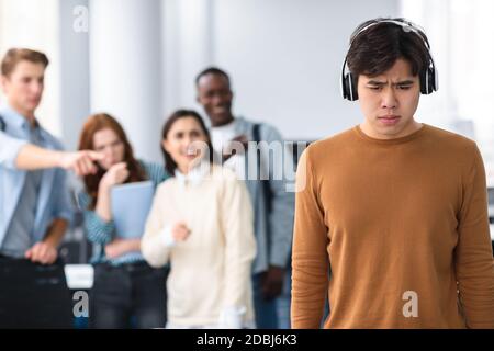 Les gens se moquer et se moquer d'un triste homme asiatique Banque D'Images