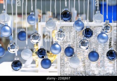 De petites boules de Noël bleu foncé, bleu clair et blanc sont accrochées à des rubans blancs. Décoration de Noël. Banque D'Images