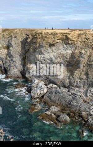 Personnes marchant le long des falaises aux Aiguilles de Port Coton, sur l'île de Belle Ile, Bretagne, France Banque D'Images